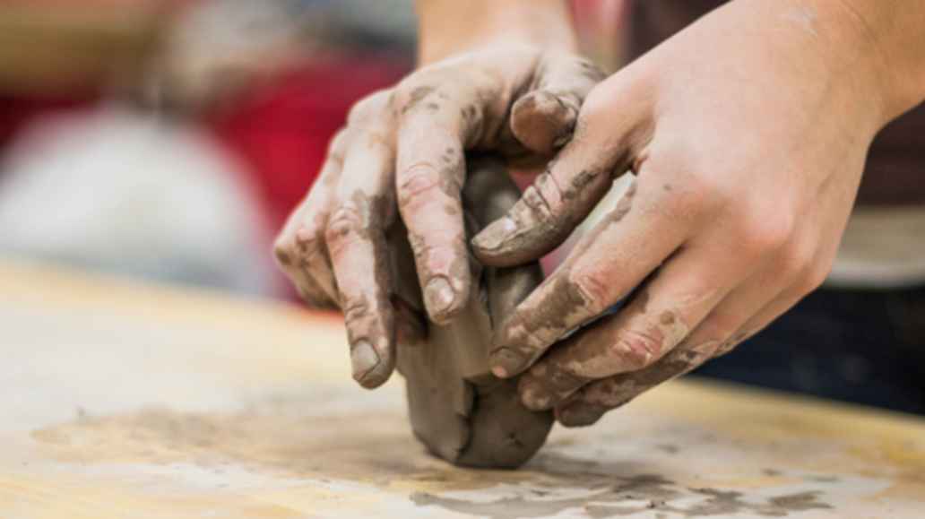 A pair of hands molding wet clay